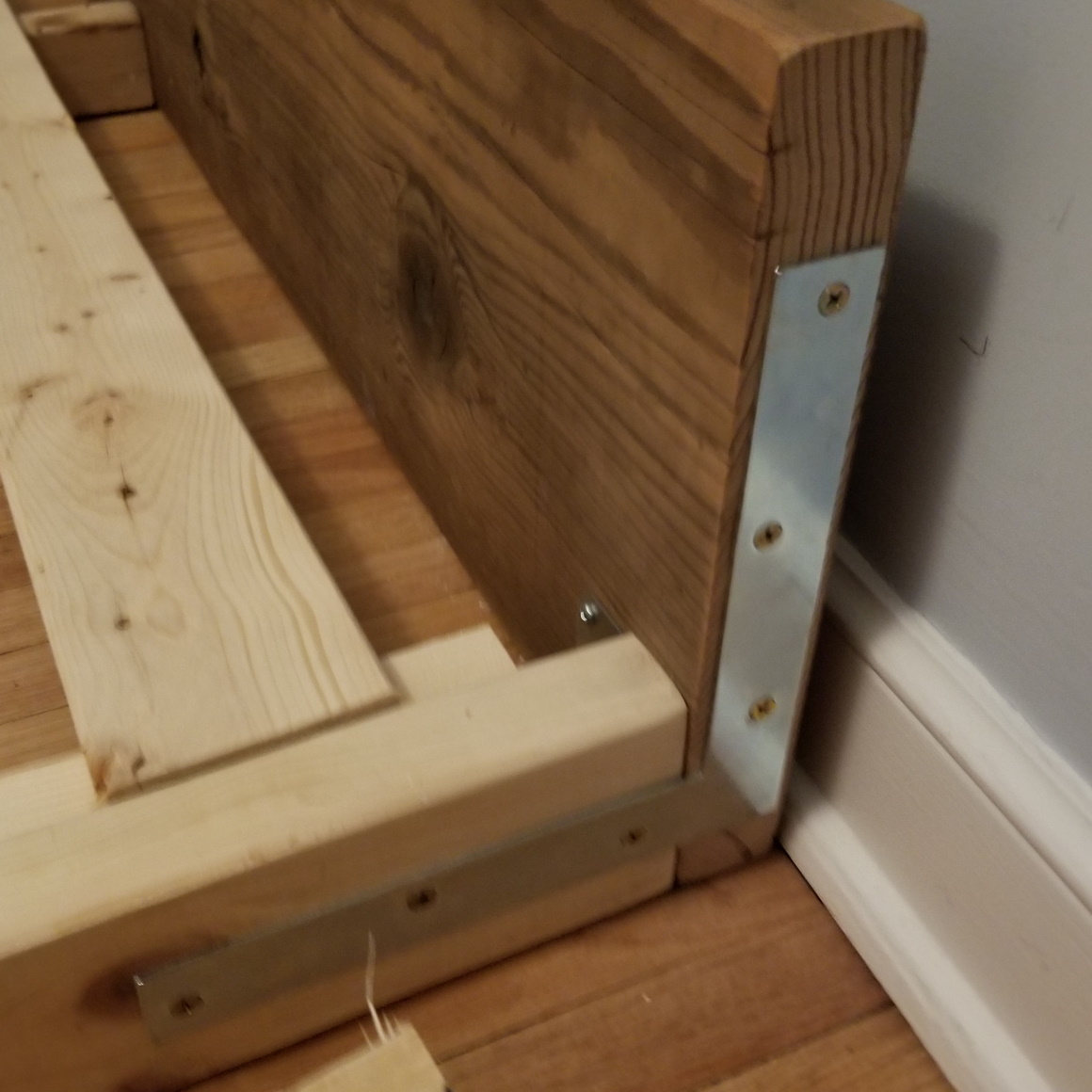 flat corner brace connecting header and frame on exterior